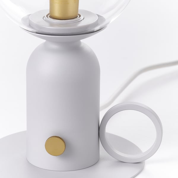 Modern table lamp with sleek white design, gold accents, and glass shade. Precise build and clean lines.