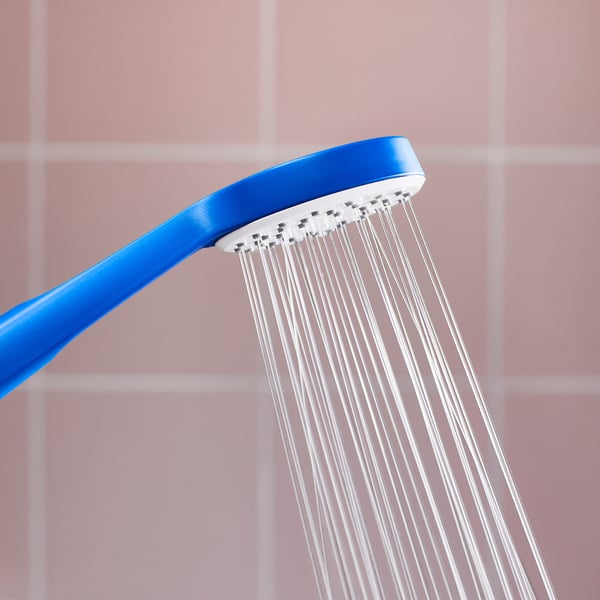 Blue shower head pouring water against pink tiled wall.