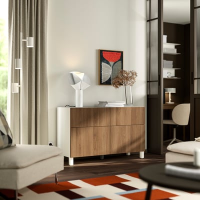 Modern minimalist room with BESTÅ sideboard, lamp, dried flowers, rug, armchair, window, and bookshelf.