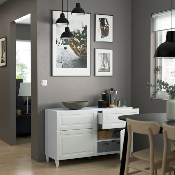 Modern dining room with a white BESTÅ sideboard featuring adjustable shelves, drawers with push-openers, and decorative items on top.