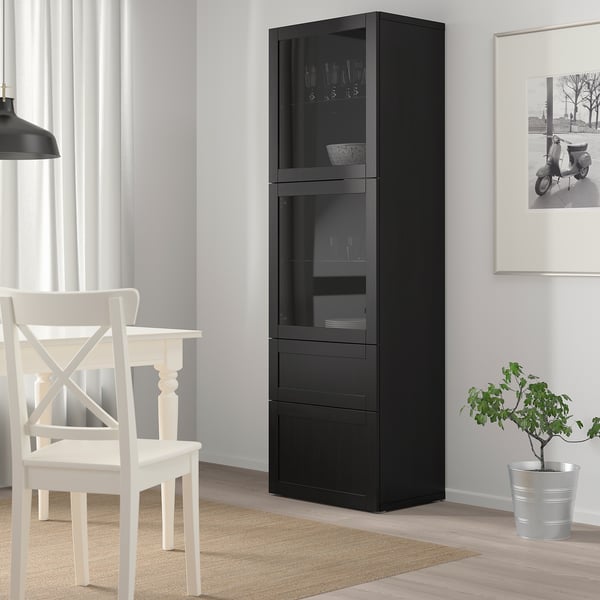 Black BESTÅ glass-door cabinet. Multiple shelves. Between chair & art wall.