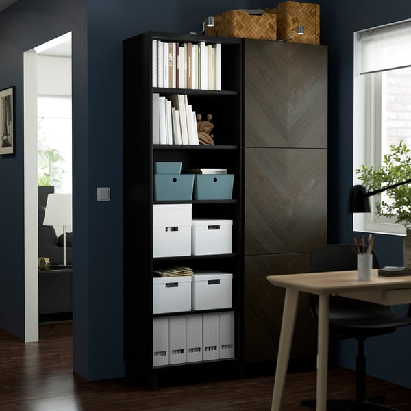 Modern office with BESTÅ shelves, wooden table, and lamp.