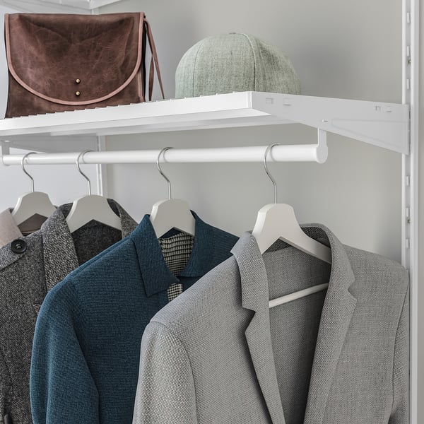 White closet with grey suits and a shelf holding a brown bag and a green hat.