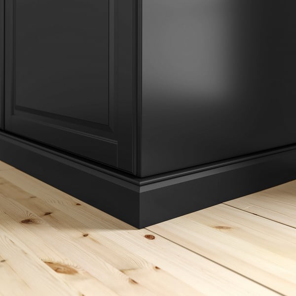 Black wooden base cabinet plinth on light wood floor, shown corner view. Part of metod series.