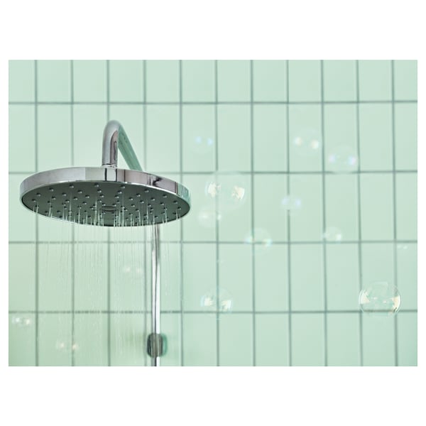 Modern silver rain shower, running water, green-tiled wall.