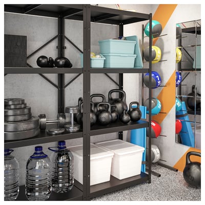 Home gym black BROR shelving system storing water bottles, kettlebells, and plastic containers. Gear organised neatly against grey wall.