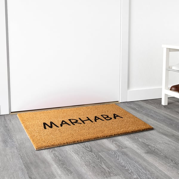 Welcome mat with marhaba on natural fibre by door.