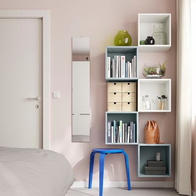 Modern bedroom with pink walls, EKET storage, books, vases, makeup, blue stool.