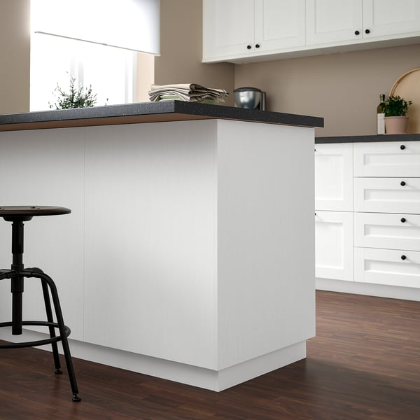 Modern white kitchen island with dark countertop, smaller than surrounding cabinets.