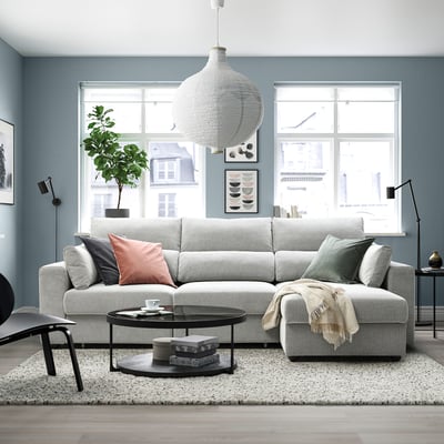 Grey ESKILSTUNA sectional sofa, plush cushions, high backrests, with coffee table and rug in modern living room.