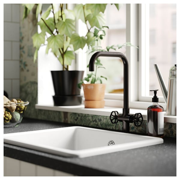 Modern kitchen sink with black GAMLESJÖN tap featuring two handles and a high spout. A potted plant sits nearby on the counter.