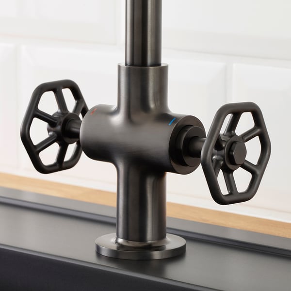Dark industrial-style tap with large black handles and high spout.