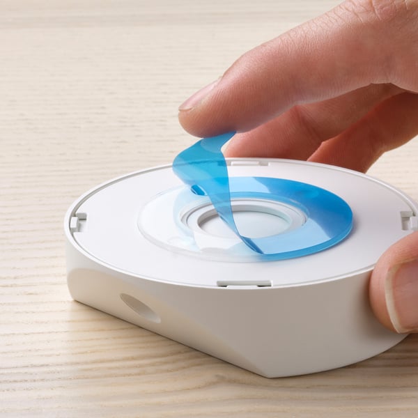 A hand removes a blue cover from a white motion-sensor light, revealing its functional sensor.