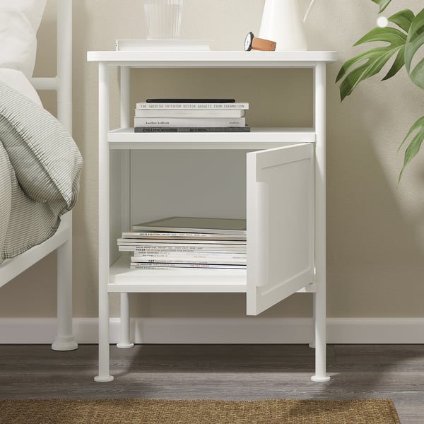 White bedside table with open shelf, closed cabinet, and books.