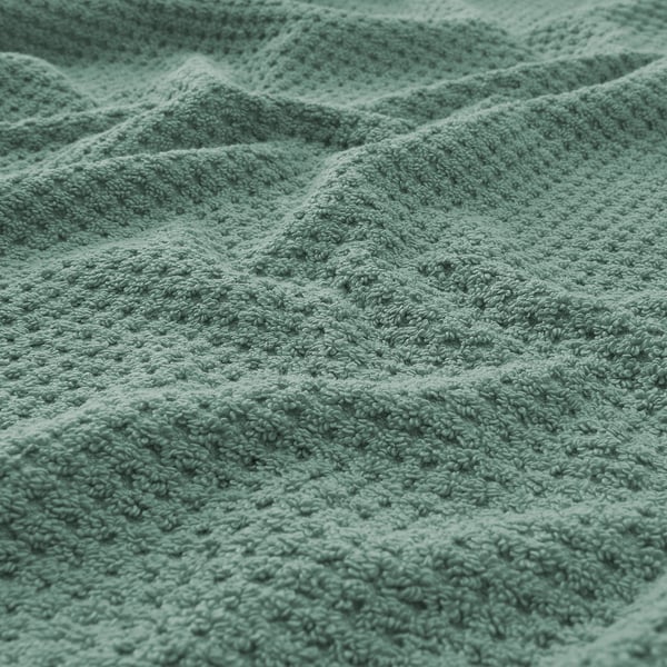 Close-up of soft, textured green towel, showcasing its fluffy, absorbent quality.
