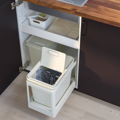 A white HÅLLBAR waste sorting bin under a kitchen cabinet, with a lid open filled with recyclables,-innovative & practical design.