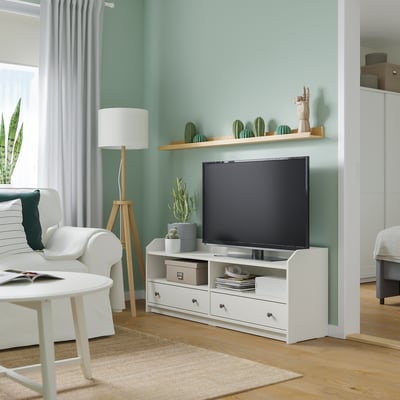 Modern living room with white tv stand, flat screen, cacti decorations, potted plants, and a cosy seating area by the window.