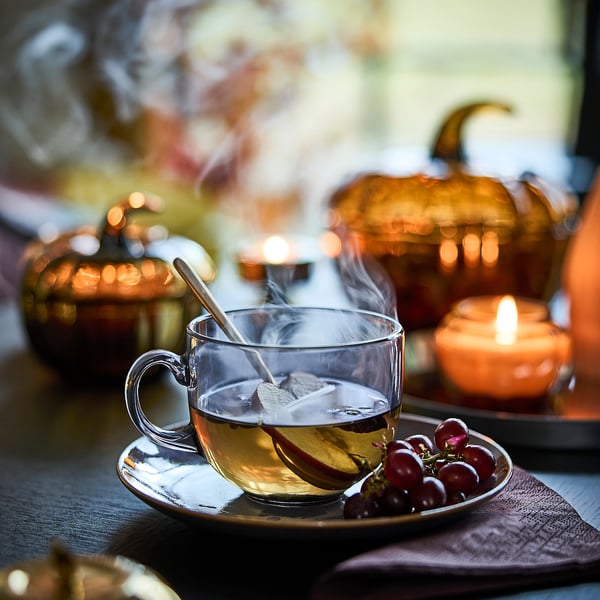 Glass mug with tea, tea bag, fruit slice, grapes. Autumn collection.