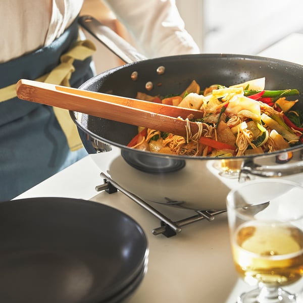 Cooking stir-fry in wok with tongs.