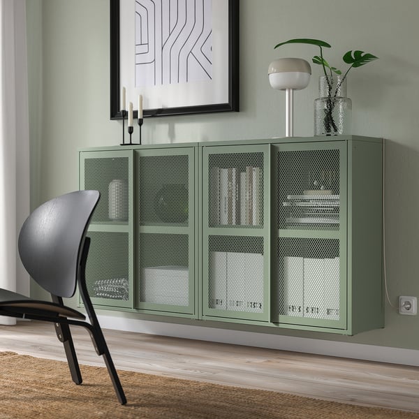Green IVAR metal cabinet with mesh doors, modern industrial design, fits under a painting.