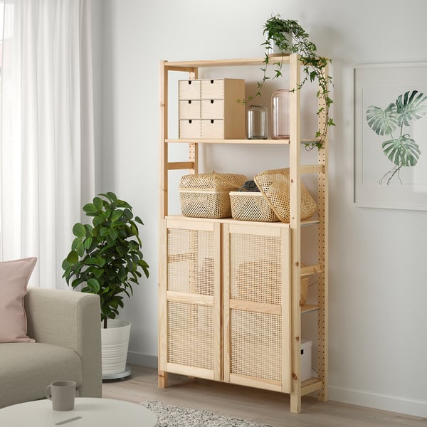 Lightwood IVAR shelf with bamboo doors in bright living space, holding storage between sofa and plant.