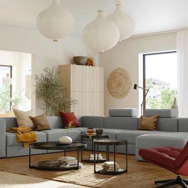Modern living room with grey JÄTTEBO sofa, wooden cabinet, hanging lights, and colourful pillows.