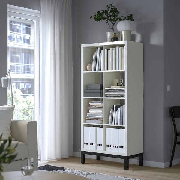 White KALLAX shelf by window, books, decor, chair.