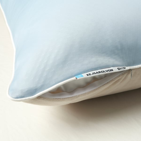 Close-up of a pillow protector with a light blue and beige side, featuring a white zip and brand tag.