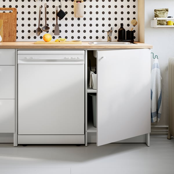 Modern kitchen with open dishwasher, wooden counter, and polka-dot backsplash. Various cooking tools and utensils organised neatly.