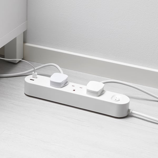 White multi-socket with usb ports on wooden floor. Charges and powers devices efficiently.