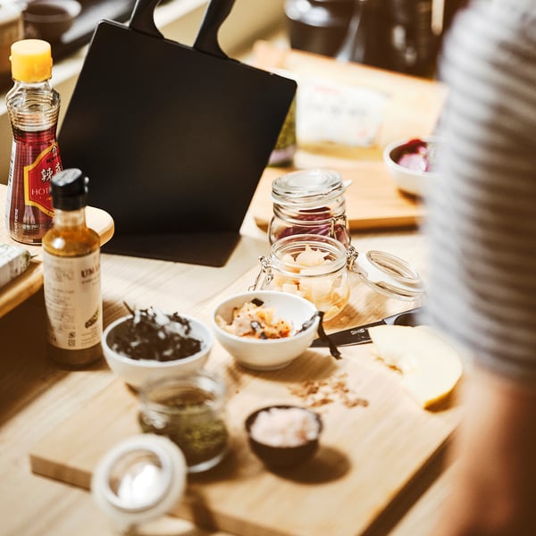 Wooden table with pickles, condiments, and a laptop. KORKEN jars are used for airtight storage.