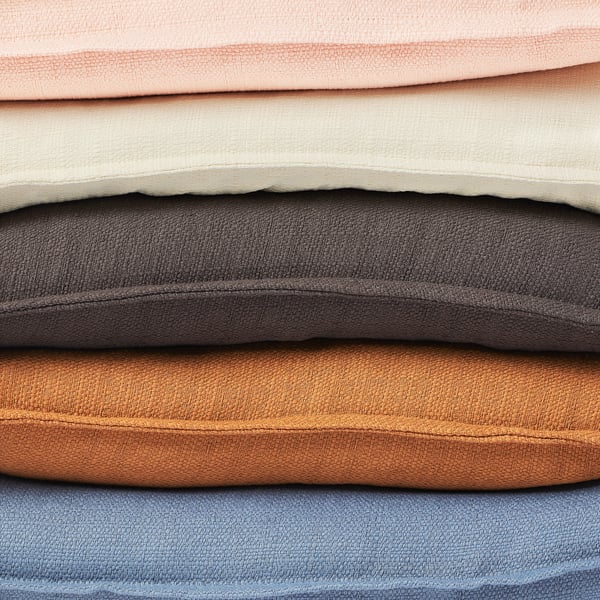 Stack of LAGERPOPPEL cushion covers in various colours, recycled polyester, textured matte-sheen, zip design.