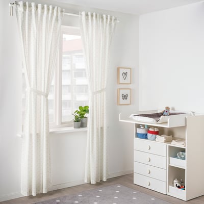 Bright nursery with white decor, heart/butterfly art, polka dot rug.