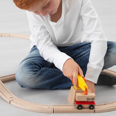 Child playing with LILLABO wooden train set, using crane to load container.