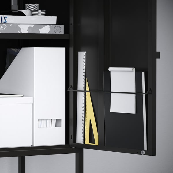 Black metal storage cabinet with open door revealing a ruler and paper holder inside.