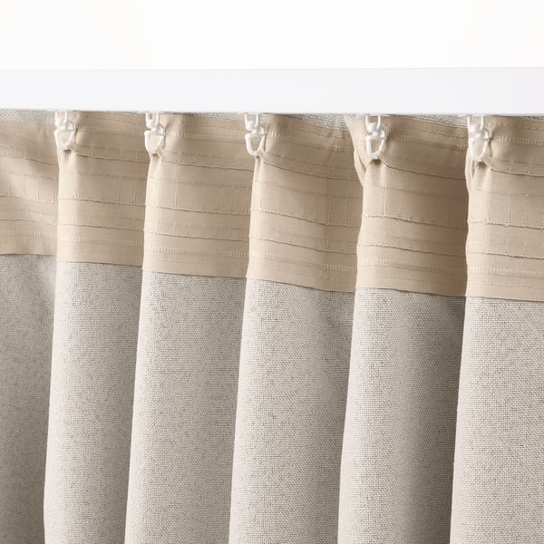 Close-up of beige LÖNNSTÄVMAL block-out curtain, showcasing its hanging hooks and textured, jacquard-weave pattern.