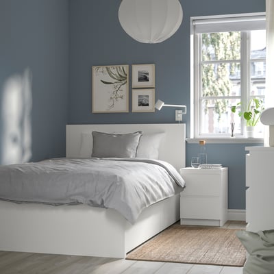 Serene bedroom with MALM bed, storage, plant, lamp, art, and window.