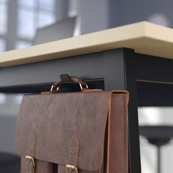 Close-up of a stylish brown leather laptop bag with a sturdy handle, resting on a modern black table.