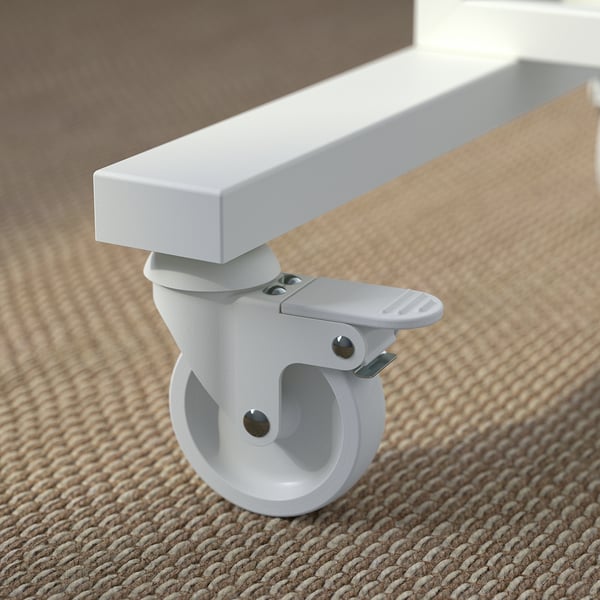 Close-up of robust, white caster wheel with brake, attached to metallic frame, on woven carpet.
