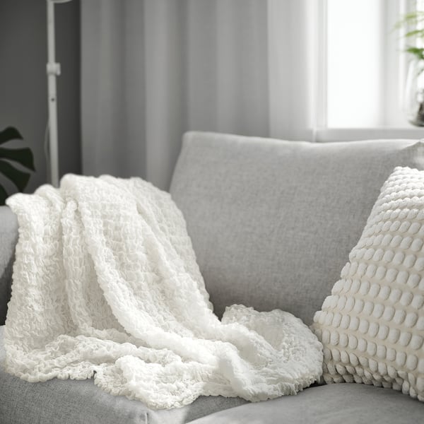 OFELIA throw blanket on grey sofa, 100% recycled polyester, soft & cosy.