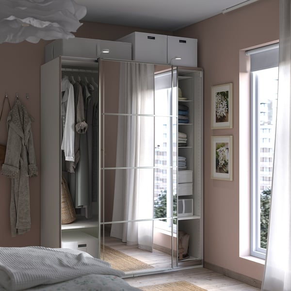 Modern bedroom with PAX wardrobe, mirrored sliding doors, grey fabric, organised clothes, white bed, large window.