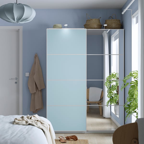 Light blue PAX wardrobe with mirror doors, clothes, baskets, towel,near bed.