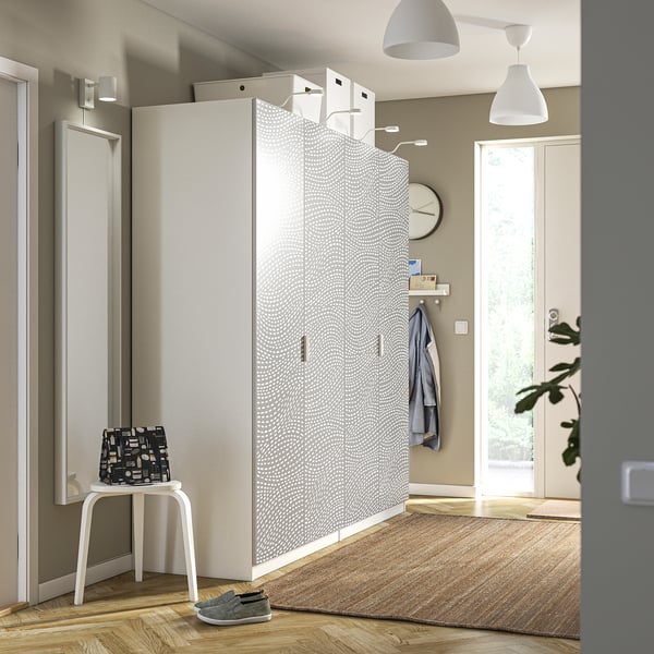 Modern closet with textured white door, grey mat, blue jacket, and small table with backpack in entryway.