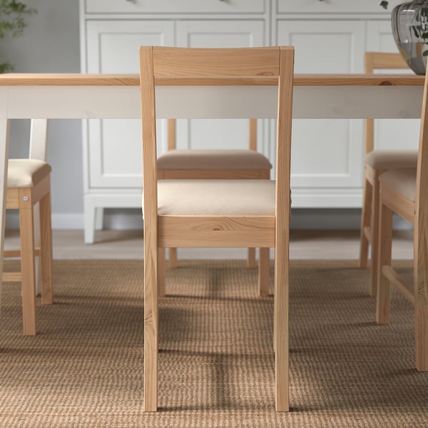 Minimalist wooden chair with upholstered seat at a table, showcasing its comfortable design for long seating.