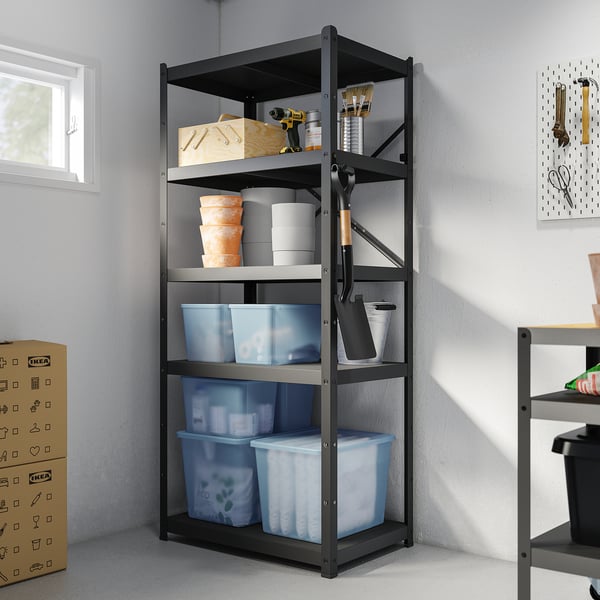 Black RYKTA organiser shelf with large blue plastic bins on bottom, white and orange bins in middle, and tools on top. Various items placed around.