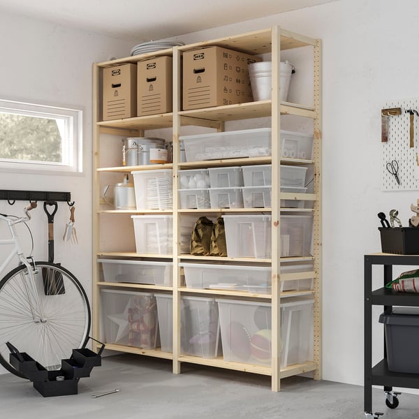 Garage storage shelves with clear plastic boxes of varying sizes, holding supplies. Bike leans against wall. Black trolley beside.