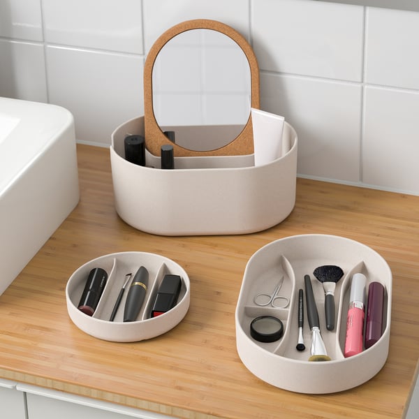 A bathroom counter with three SAXBORGA organisers. Two store beauty products; one with a mirror top holds makeup.