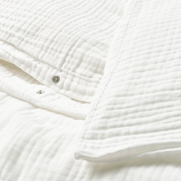 Close-up of a white SCHERSMIN duvet cover with visible press-stud closure and wavy texture.