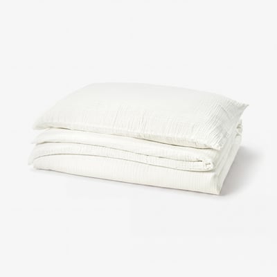 A neatly folded SCHERSMIN duvet cover set in white, made of soft organic cotton.