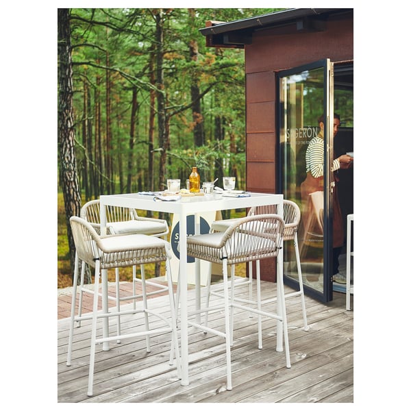 Outdoor dining set, white, metal, wicker. Patio table, 4 stools, forest view.